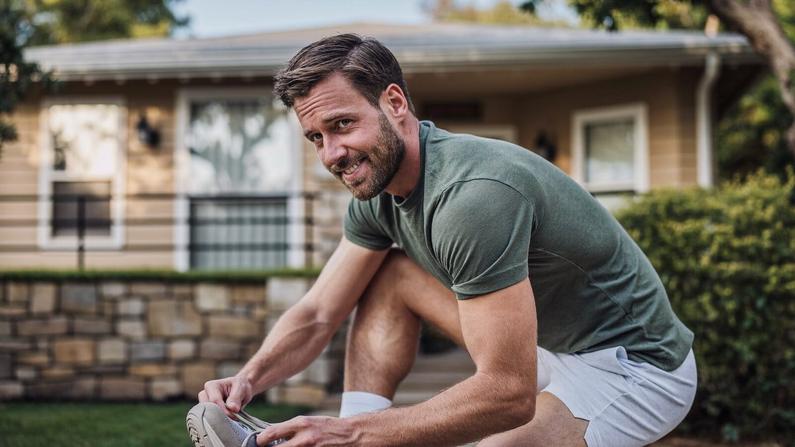 Man in his 30s tying his sneakers outside his house in the morning