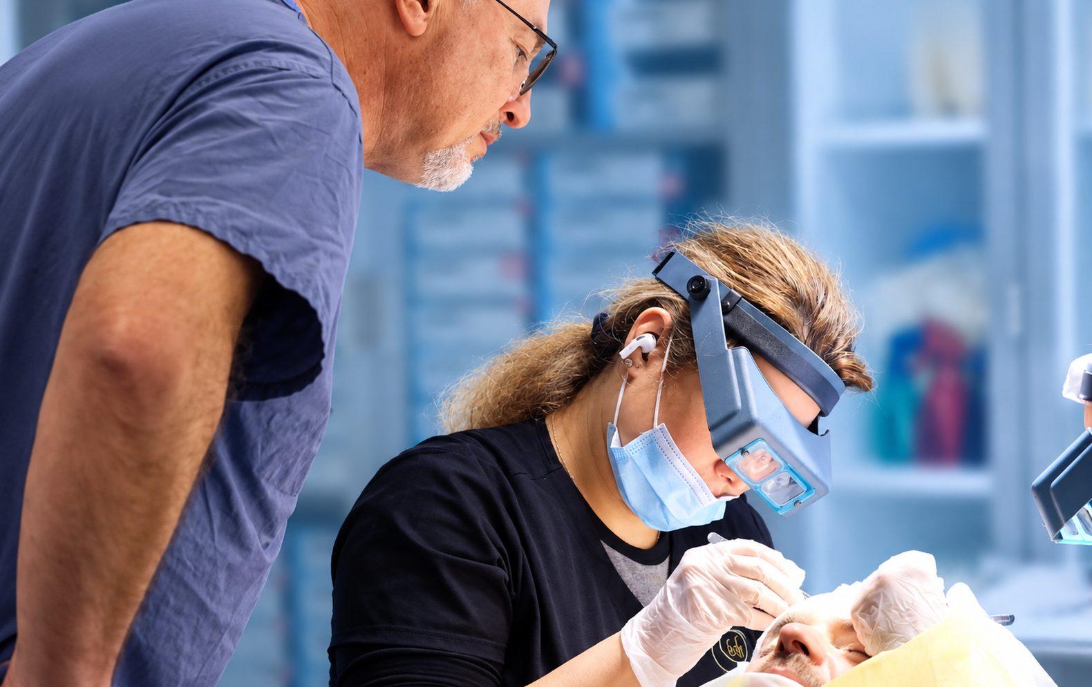 Technician placing grafts under magnifying loupes while Dr. Val Prokurat, MD looks on during an FUE procedure at Nova Medical New Jersey